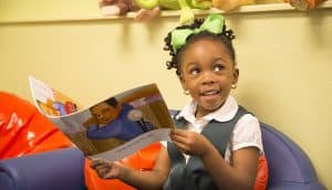 young black girl reads a book in classroom