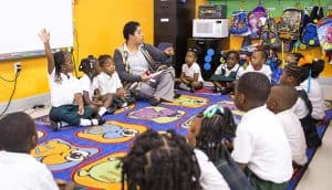 preK students sit on classroom rug with teacher and do Waterford