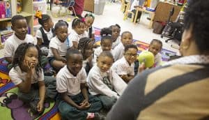 students sit on classroom rug during Waterford time