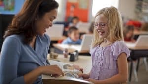 teacher shows young girl page in book
