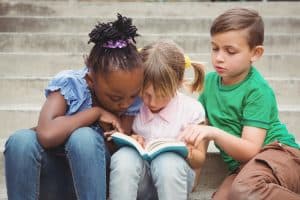Students sitting on steps and reading a book