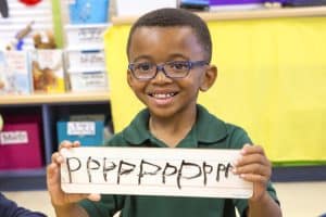 boy holding up hand written letters
