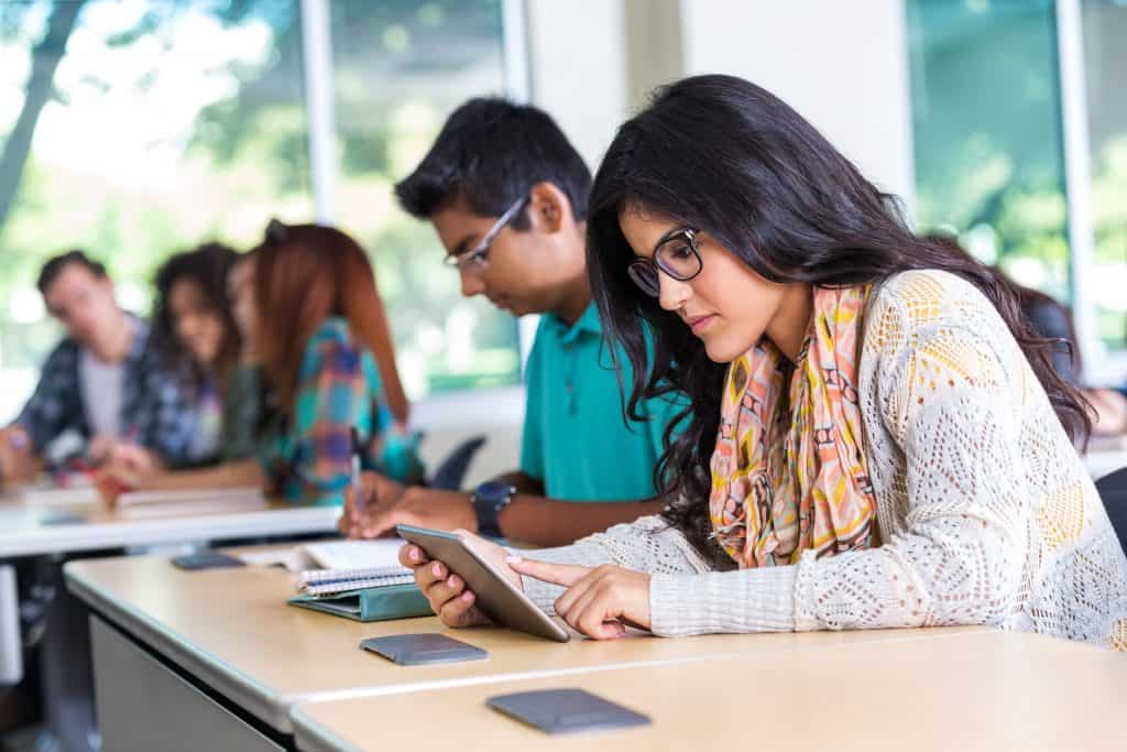 Hispanic teen using digital tablet during classroom in school
