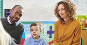 stock photo of parents and child engaging in parent-teacher meeting in school