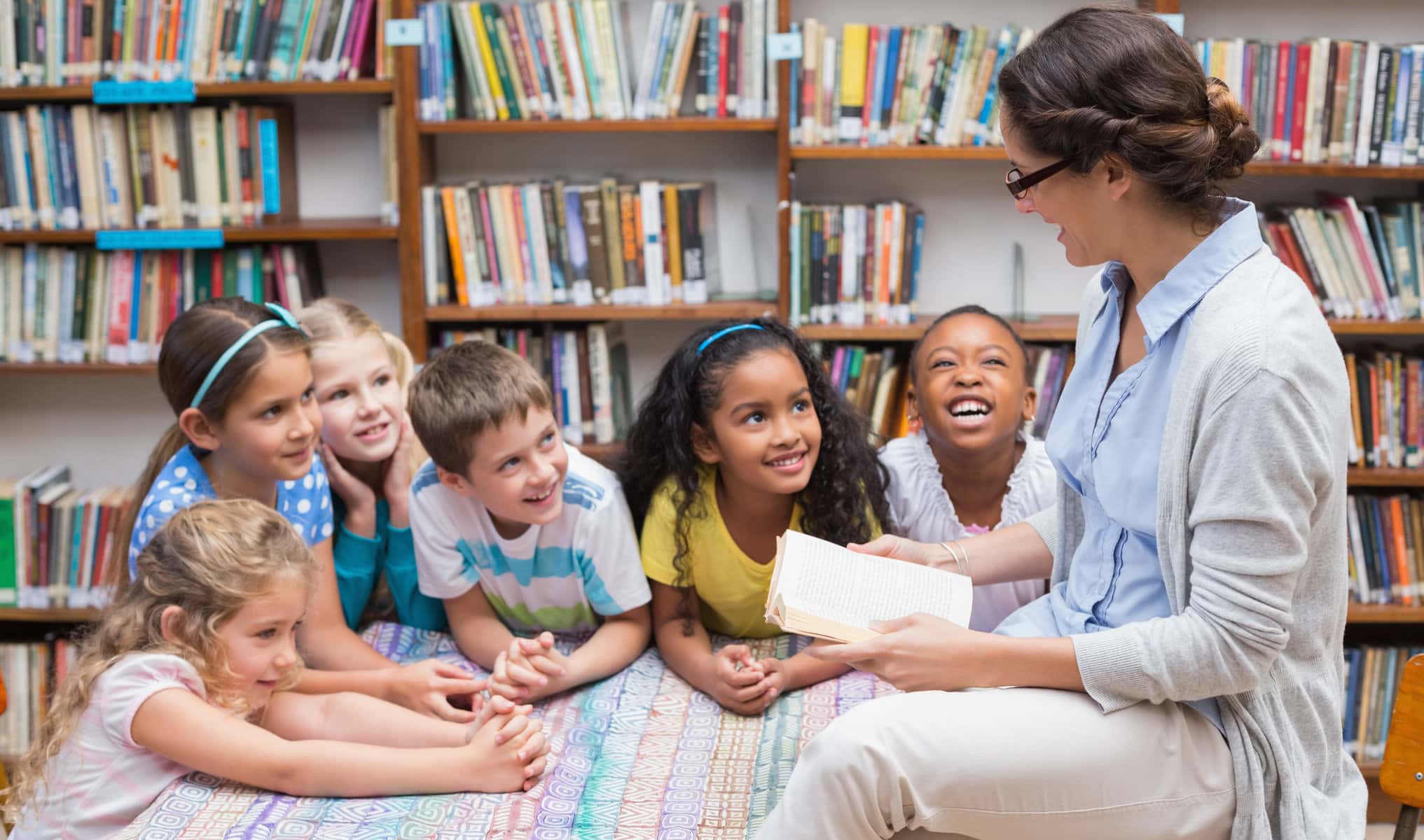 students and teacher reading a book