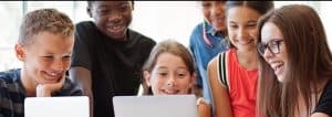 School children using laptop with teacher
