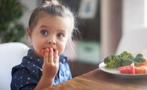 A young girl eats a healthy meal of vegetables. Find food assistance for your family.