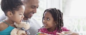 A father and his preschool and elementary-aged daughter reading together