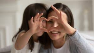 Mother and child making heart sign with hands. Gratitude can help children be happier and healthier