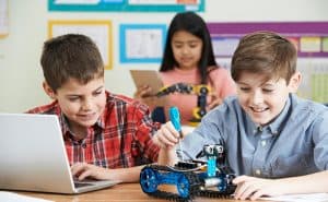 Three students work on coding and other STEM projects at tables