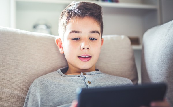 An elementary-age student reading the news on a tablet