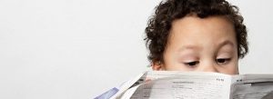 A young boy reading the newspaper
