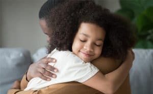 A girl is hugged by her caregiver.