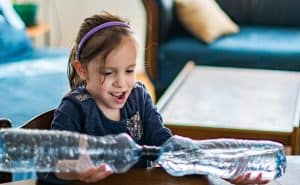 A girl makes a tornado in a bottle. Simple, reusable materials make for a fun science lesson