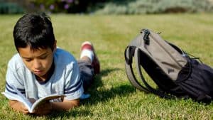 A boy reading in the grass during the summer