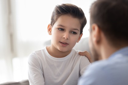 A young boy being comforted by an adult.