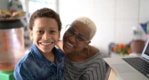 Portrait of mother helping her son studying with laptop on a online class at home