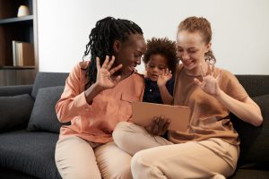 Parents and their toddler son waving with hands when video calling family member