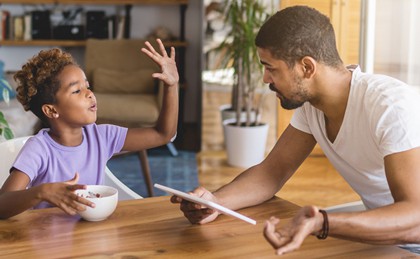 A father quizzing his daughter at the kitchen table