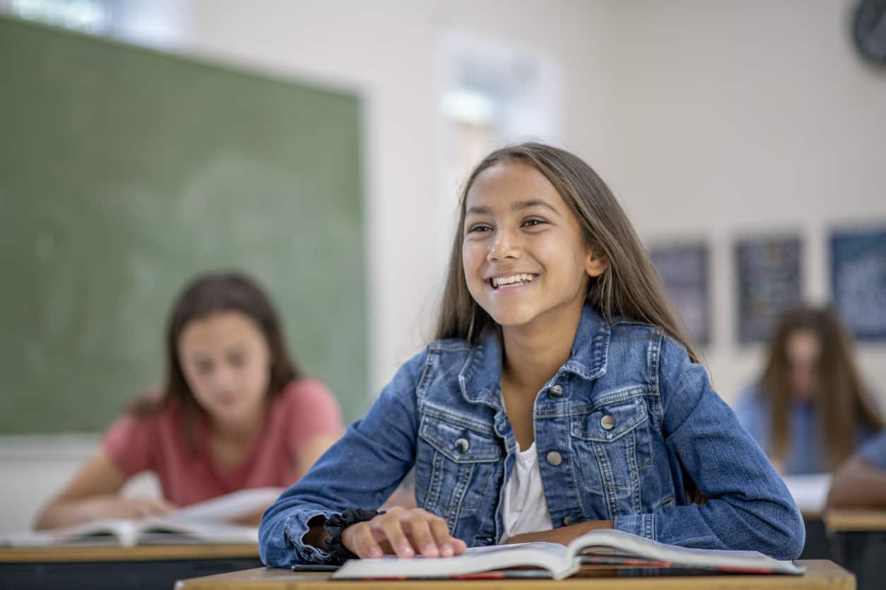 middle school student sitting at her desk in a classroom