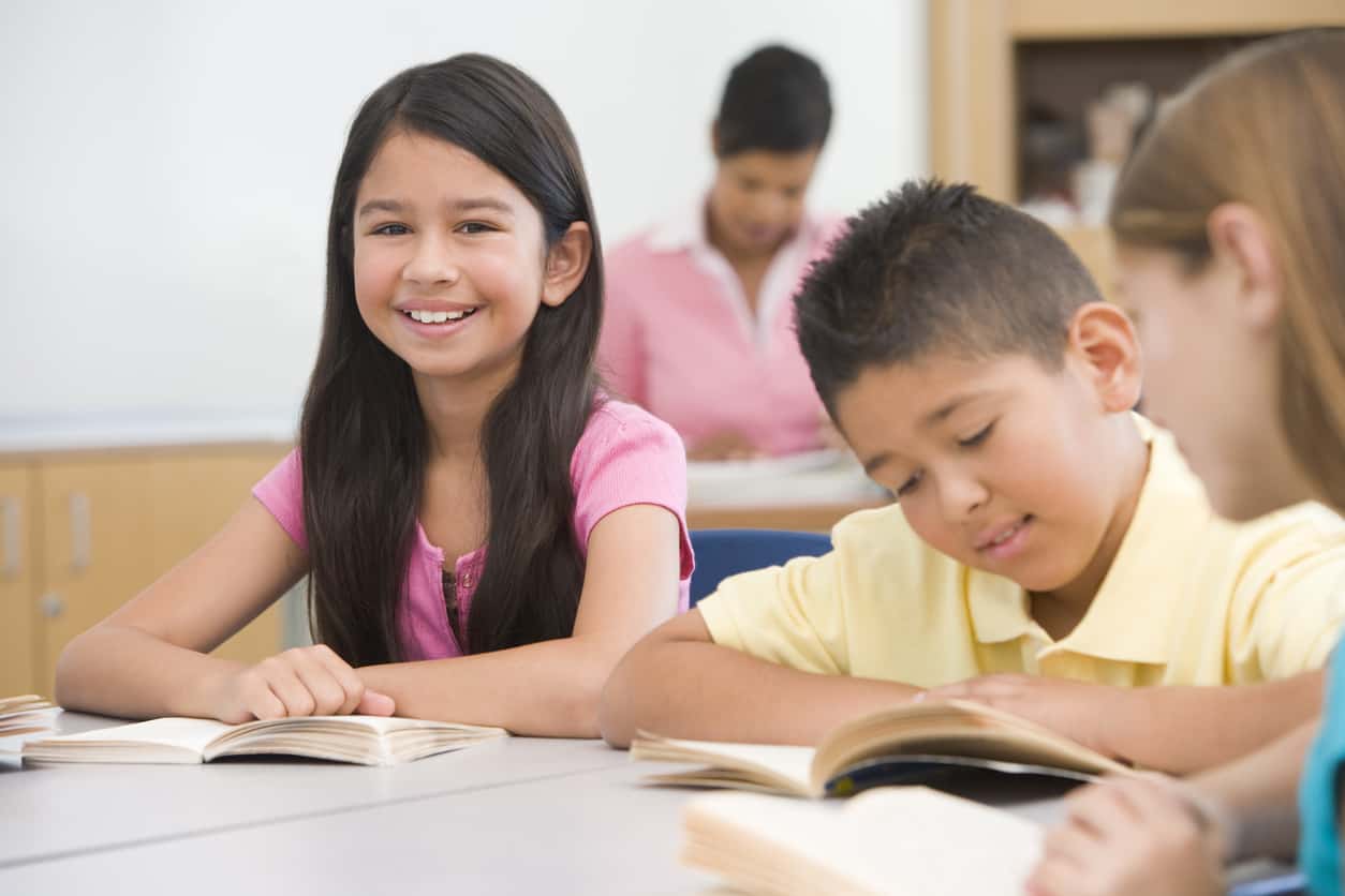 Group of elementary school pupils reading smiling