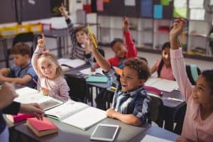 Students raising their hands in classroom at school
