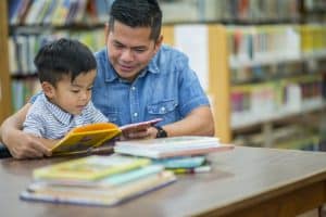 photo of a father and son reading at the library