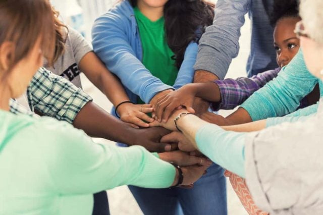 Diverse group of volunteers put hands together