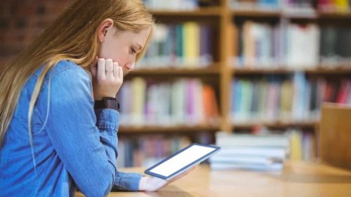 Student reading a tablet in school library