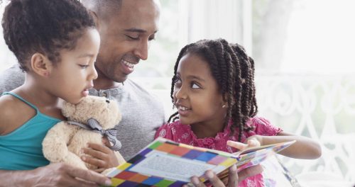 father reading to his two young daughters
